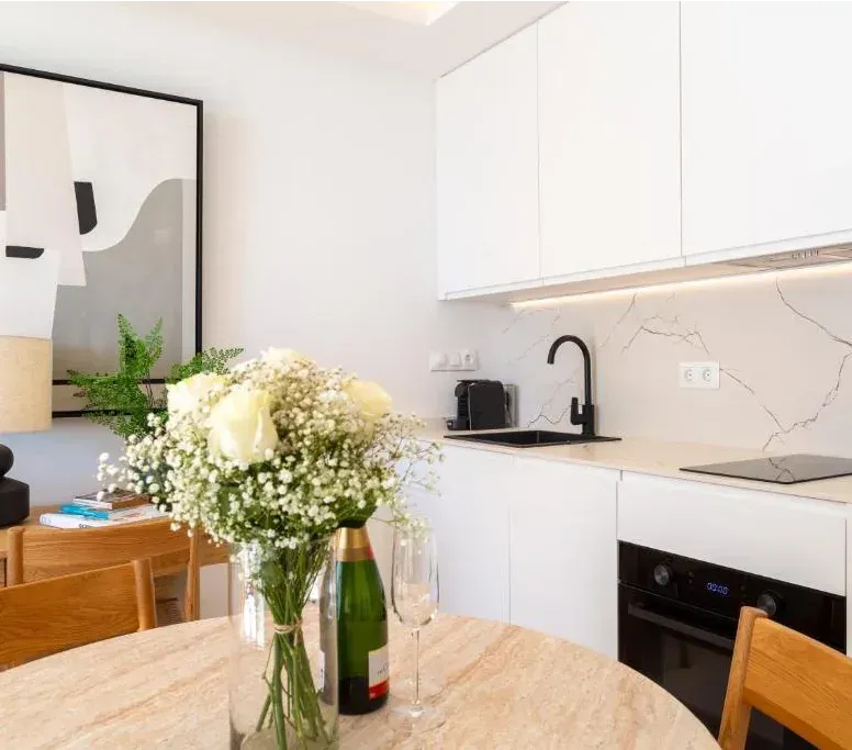 Patio exterior con mesa de madera, sillas y lámparas colgantes tejidas.