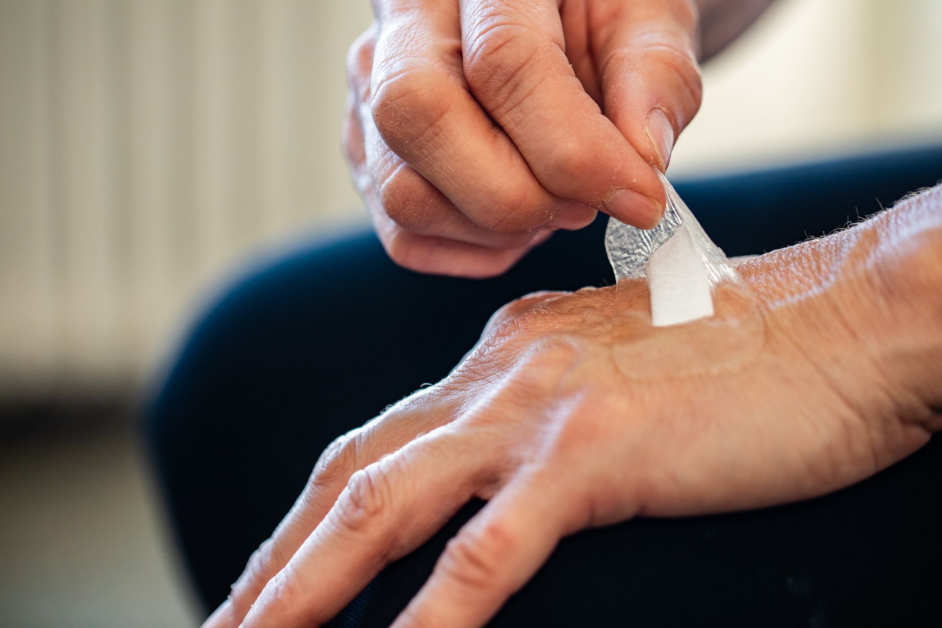 Une personne qui retire un petit pansement adhésif sur sa main.