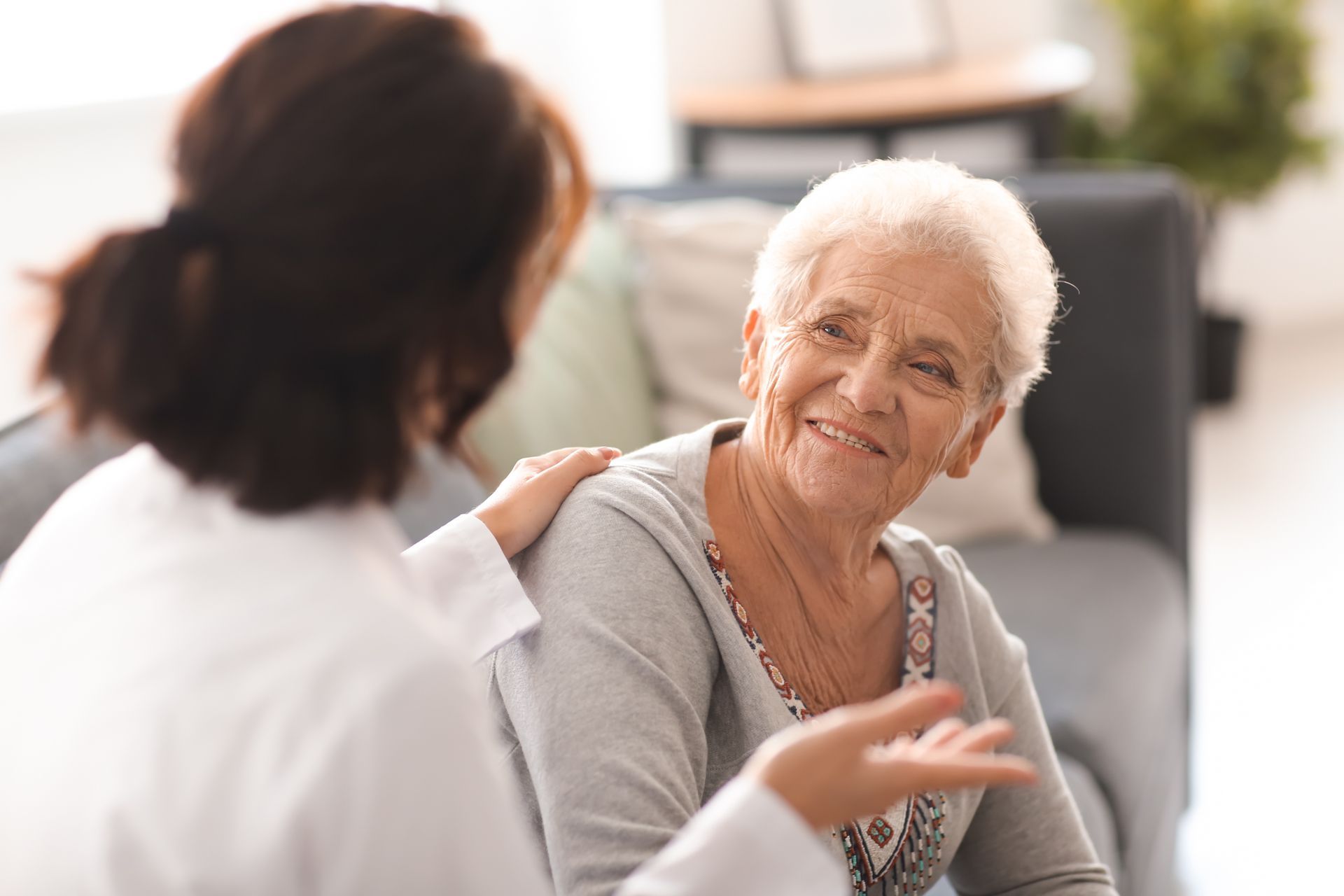 Un professionnel en blouse blanche pose la main sur l'épaule d'une personne, engageant une conversation.