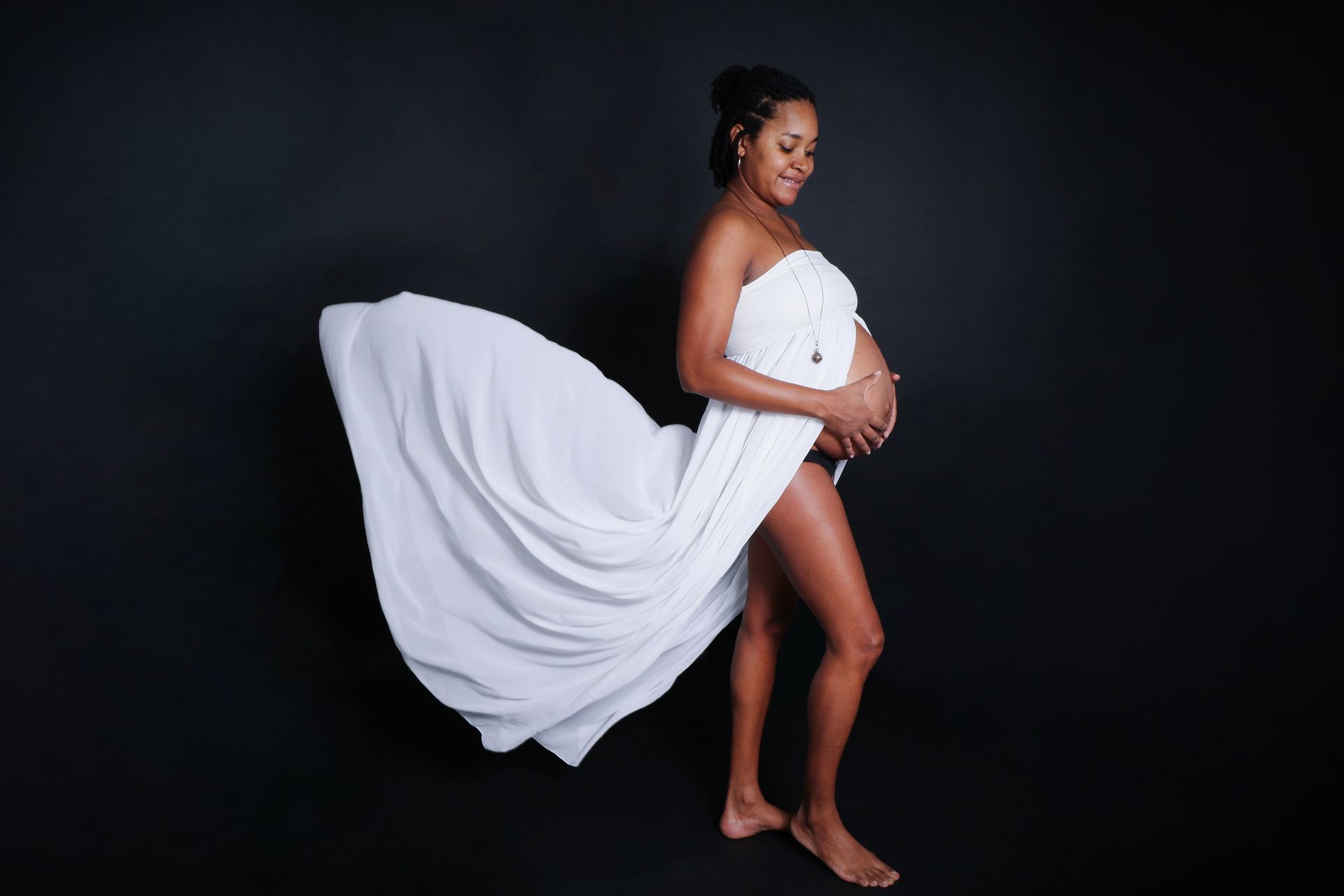 Photo d'une femme vêtue d'une robe volante qui arbore son ventre de femme enceinte