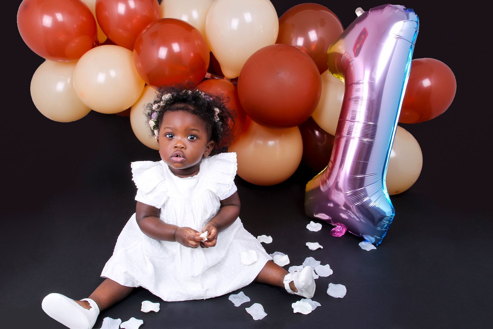 Photo d'une petite fille dans une robe blanche entourée de ballons