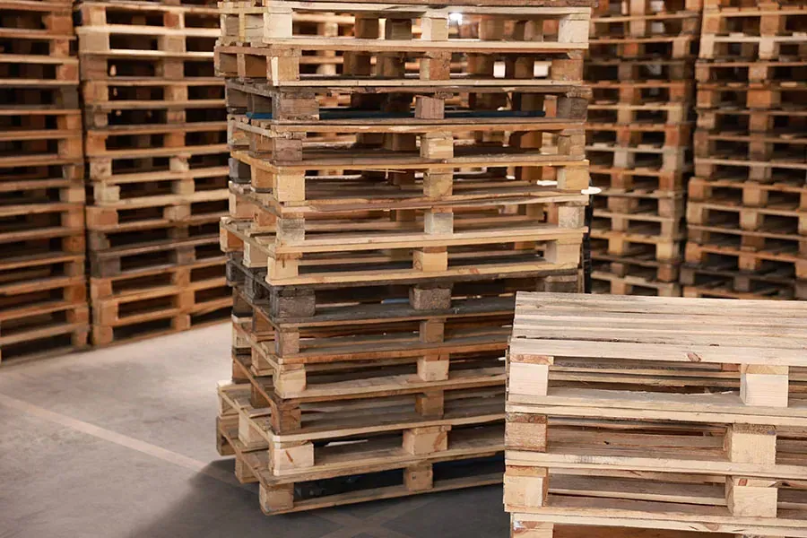 Un almacén lleno de montones de paletas de madera apiladas una encima de otra.