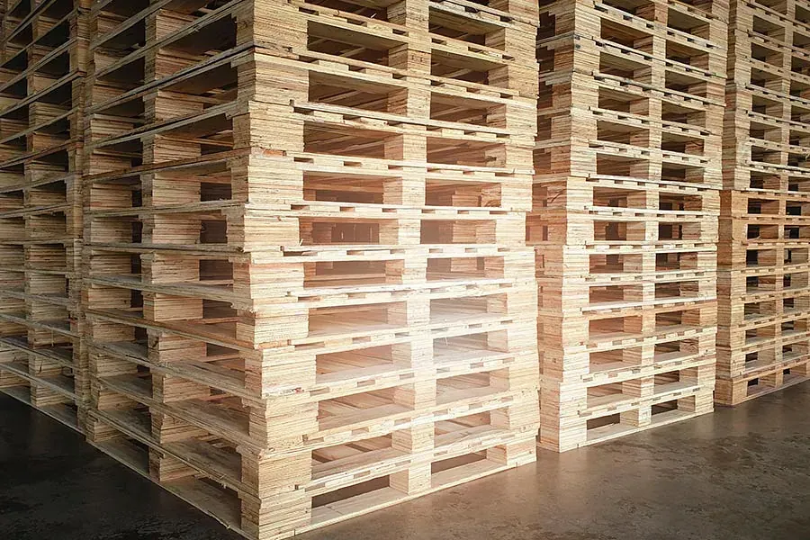 Un almacén lleno de montones de paletas de madera apiladas una encima de otra.