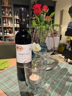 Eine Flasche Wein steht neben einem Glas und einer Vase mit Blumen auf einem Tisch.
