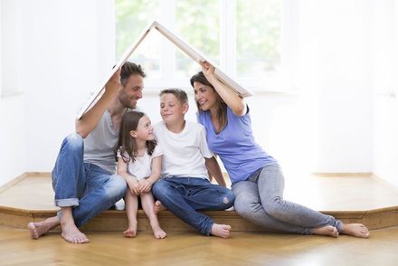 Eine Familie sitzt auf dem Boden unter einem Papphaus.
