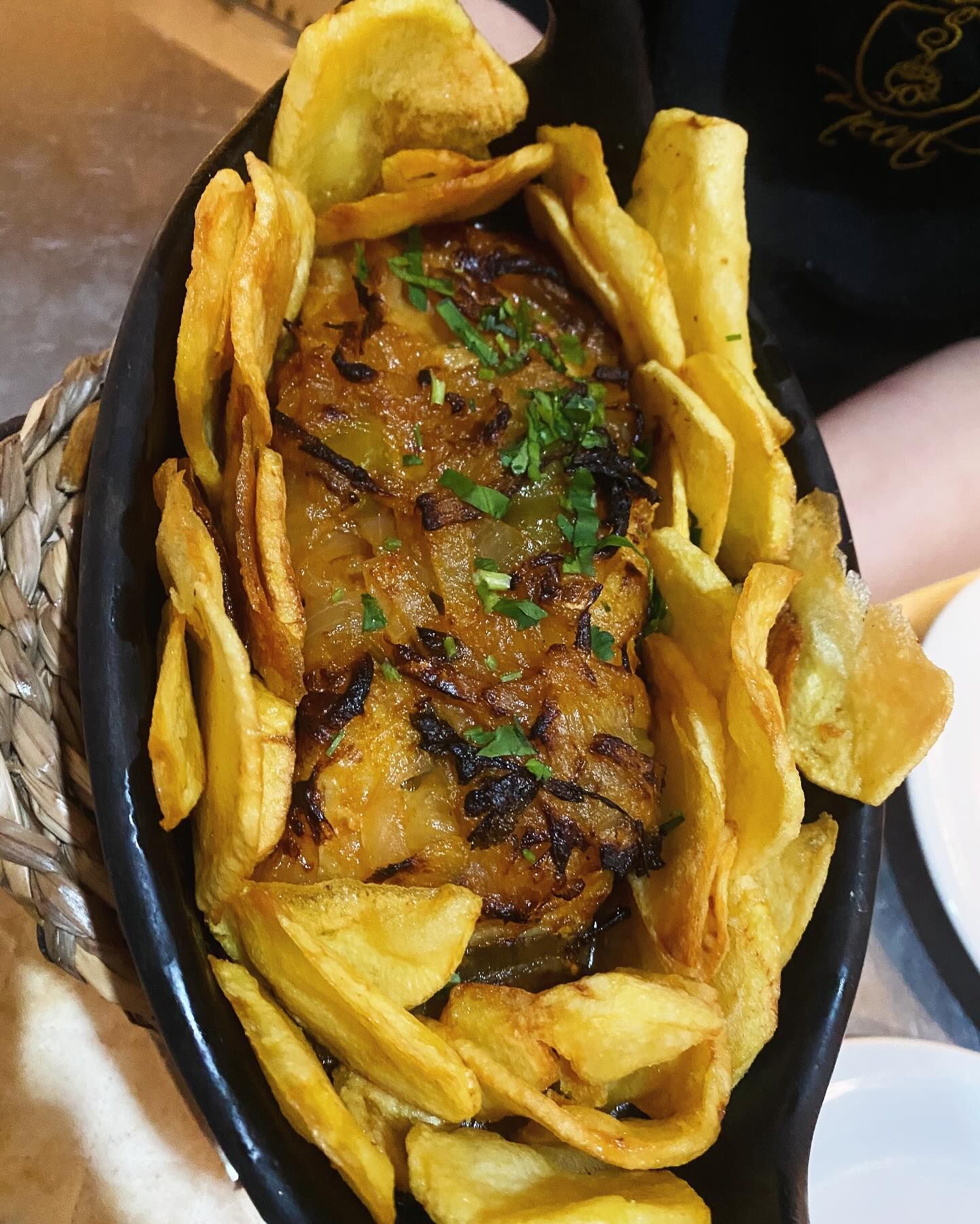 Um prato de comida com batatas fritas e carne em uma mesa