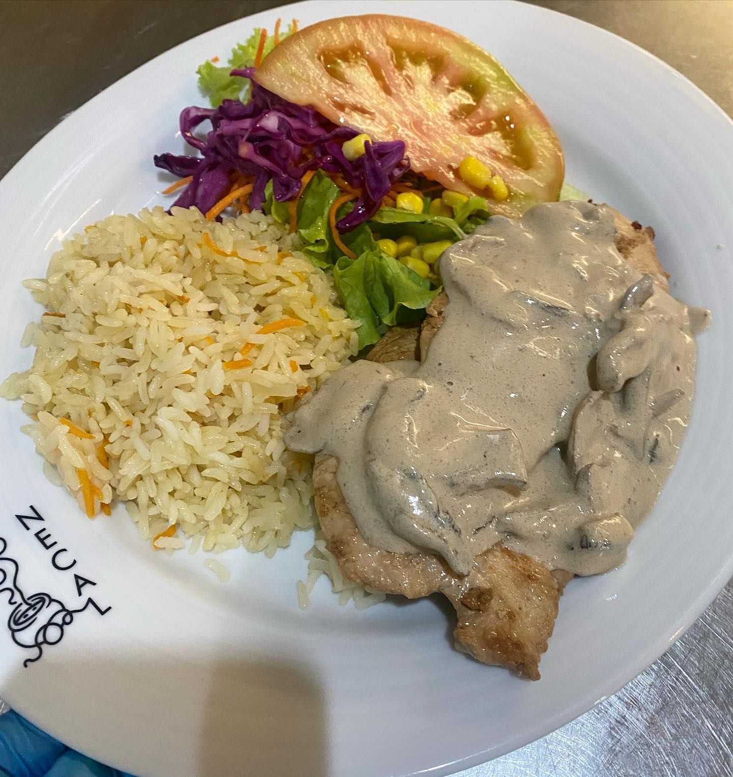 Um prato de comida com arroz, tomates e alface em uma mesa