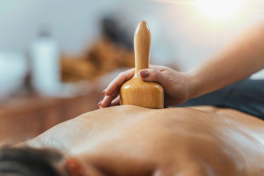 Persona que recibe masaje de espalda con herramienta de masaje de madera.