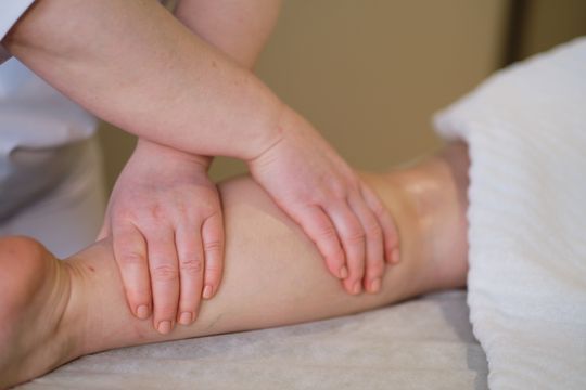 Mujer que lleva una mascarilla blanca, sosteniéndola con los dedos, sobre un fondo blanco.