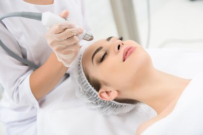 Mujer recibe un tratamiento facial con un dispositivo portátil en un spa.