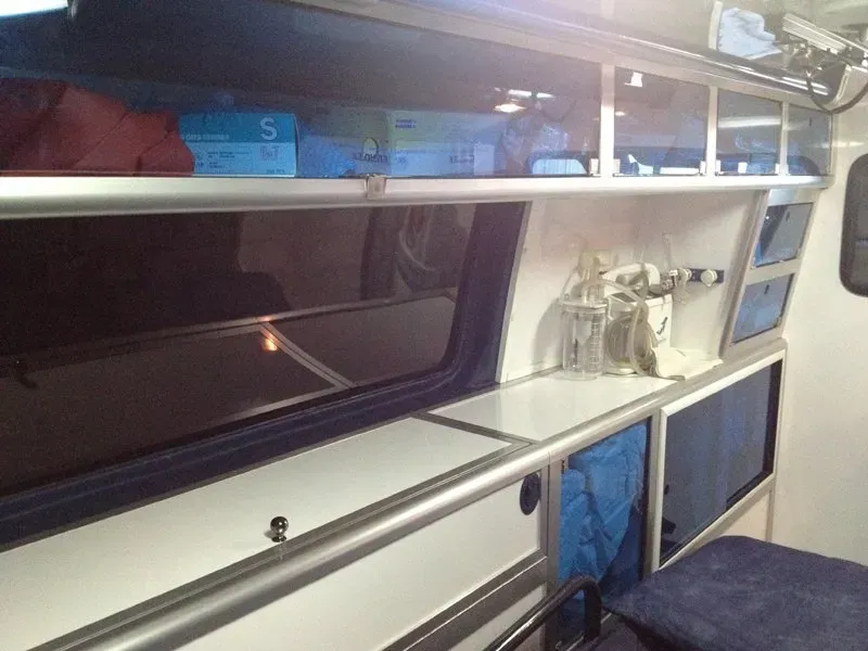 Intérieur d'une ambulance avec des armoires, une fenêtre et du matériel médical.