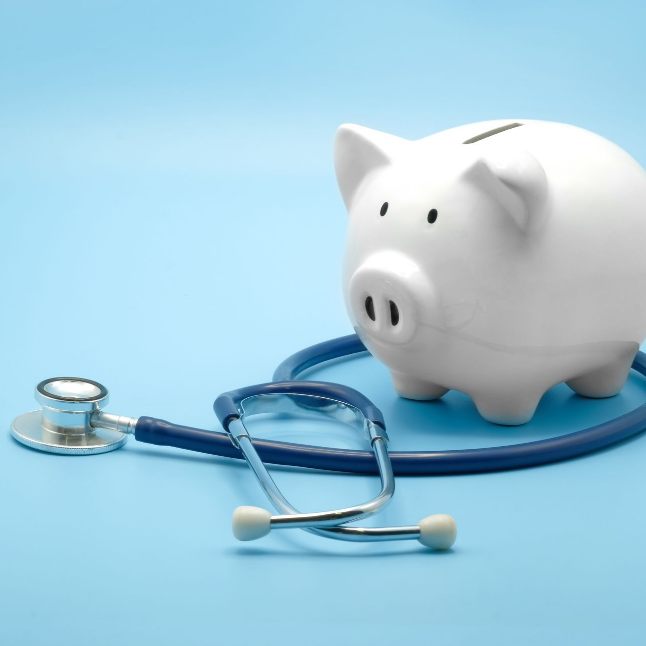 Une tirelire blanche et un stéthoscope bleu sur un fond bleu clair, symbolisant les économies réalisées dans le domaine de la santé.