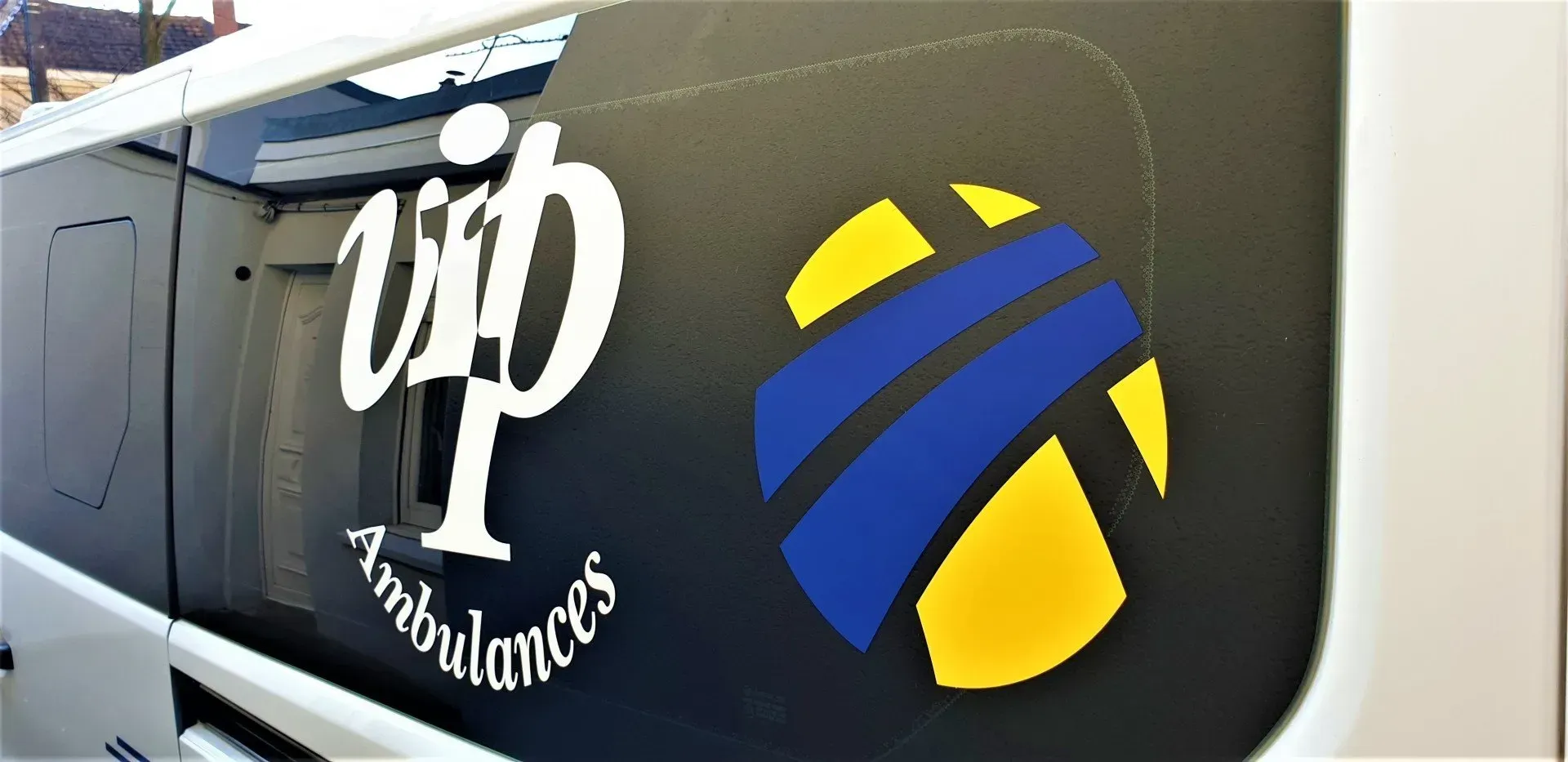 Fourgonnette noire arborant le logo VIP Ambulances et un emblème bleu et jaune.