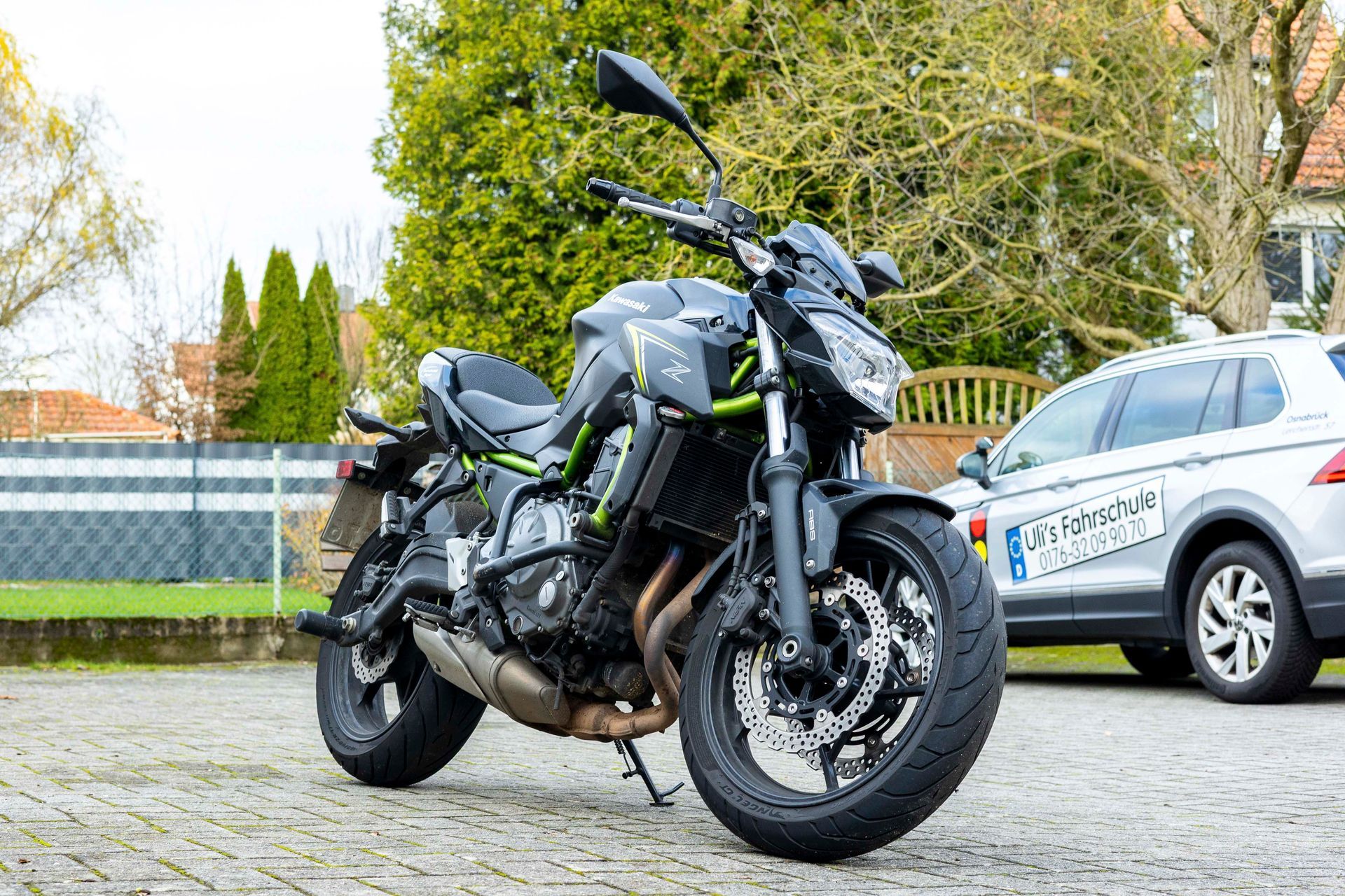 Auf einem Parkplatz steht ein Motorrad neben einem Auto.
