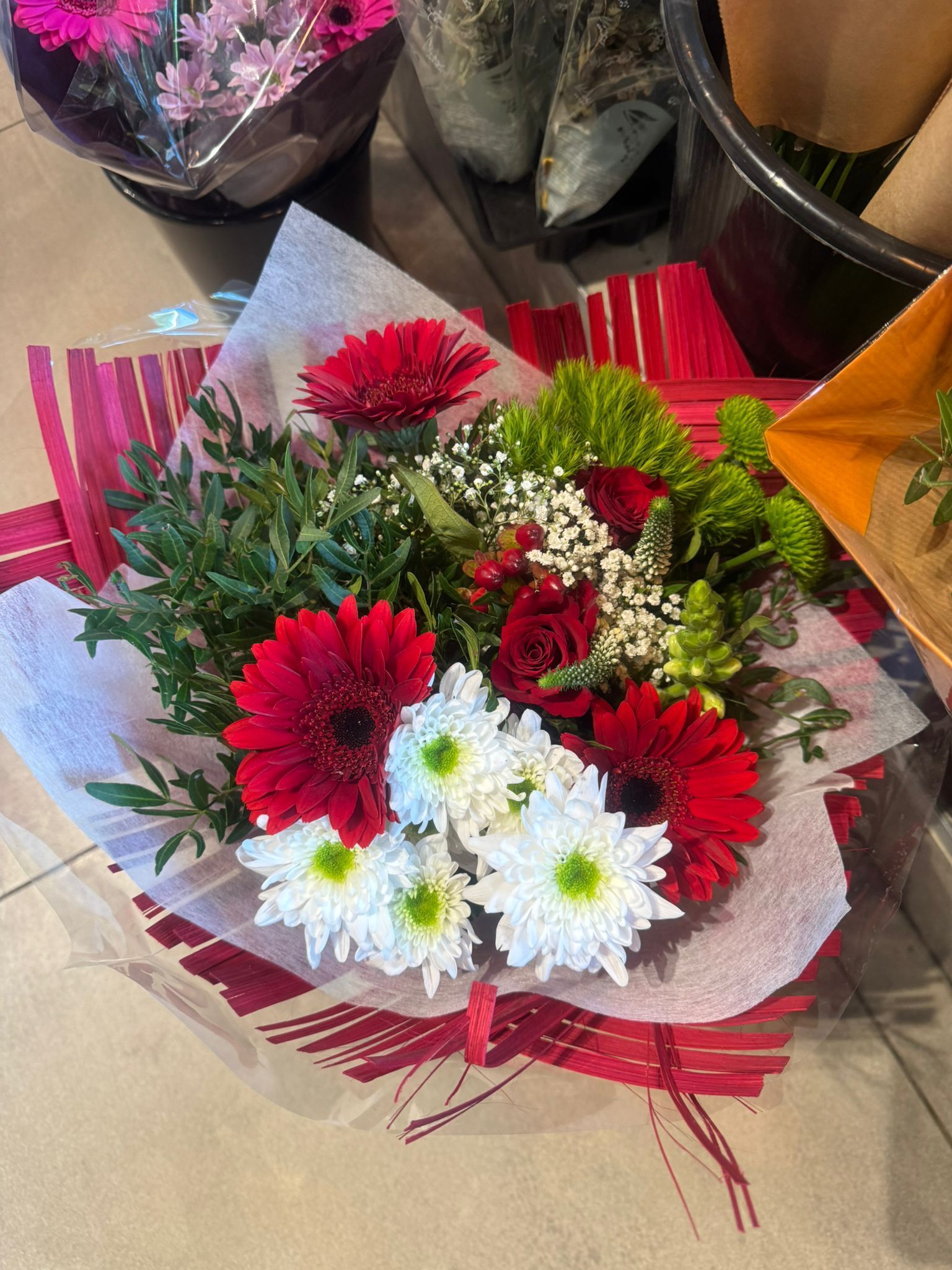 Una mujer está arreglando un ramo de rosas rosadas en un jarrón sobre una mesa de madera.