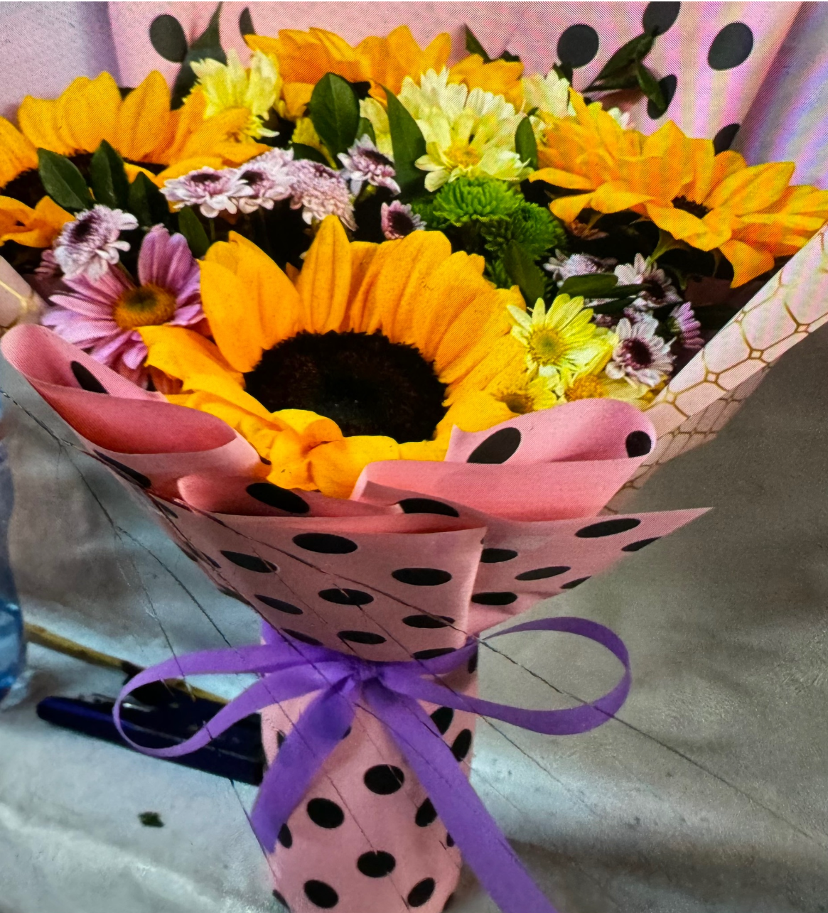 Una persona está envolviendo un ramo de flores en papel rosa.