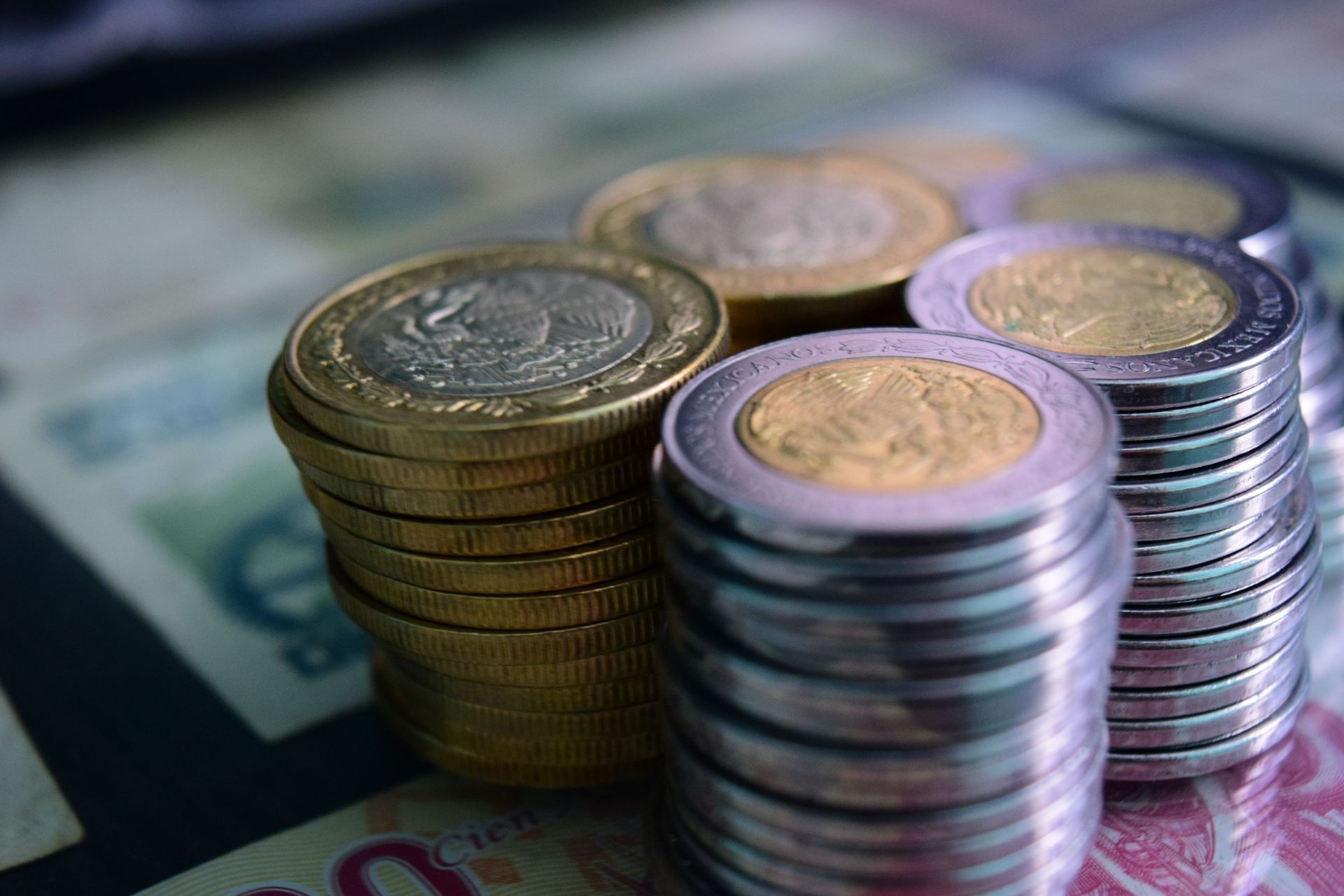 Montones de monedas variadas sobre billetes desenfocados