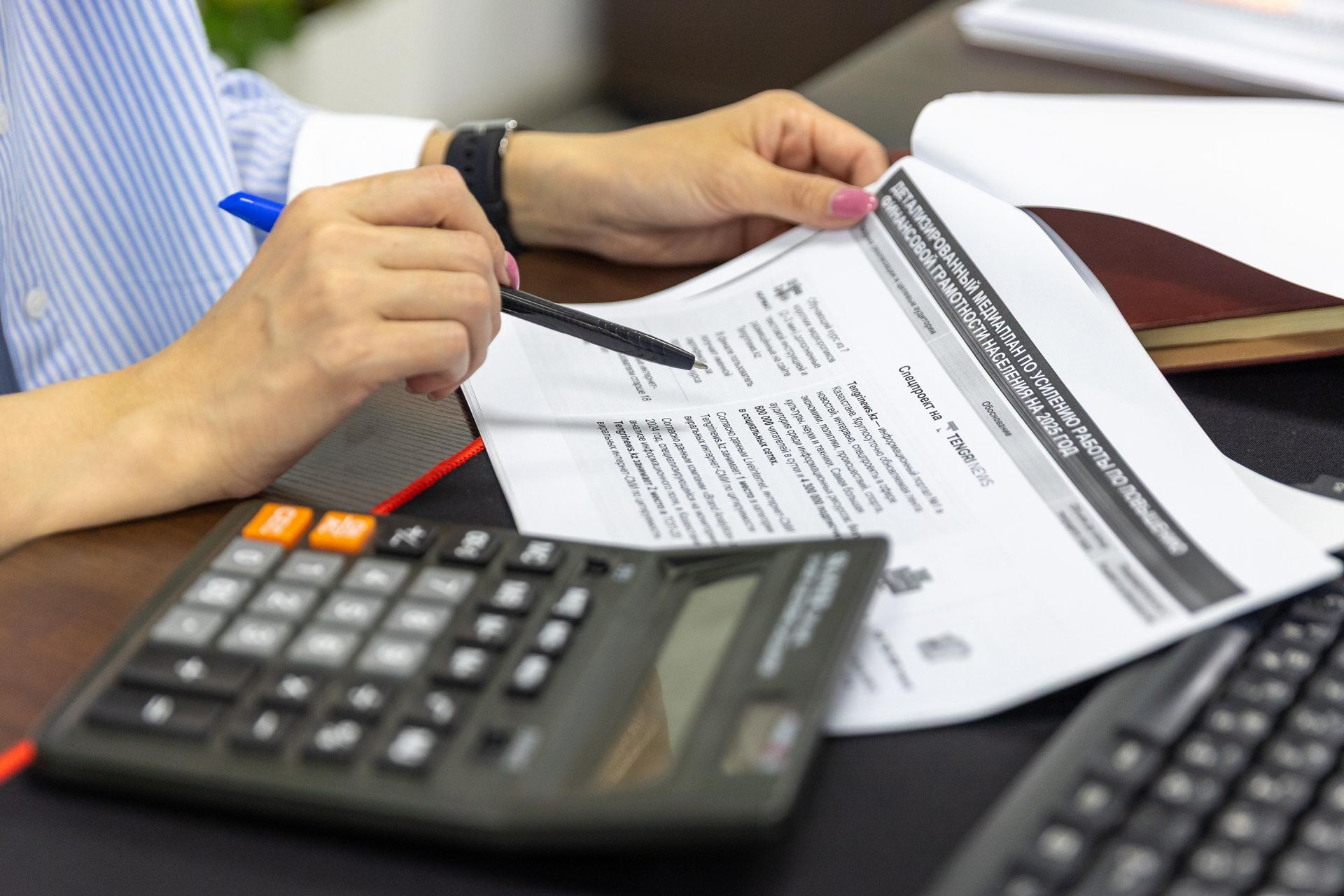 Unas manos revisan un documento impreso con una calculadora sobre un escritorio