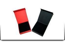 Dos cajas, una roja y otra negra, están una al lado de la otra sobre una superficie blanca.