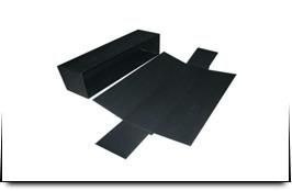 Una caja negra y un trozo de papel negro sobre un fondo blanco.