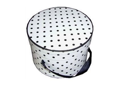 Una sombrerera blanca con lunares negros y un asa negra