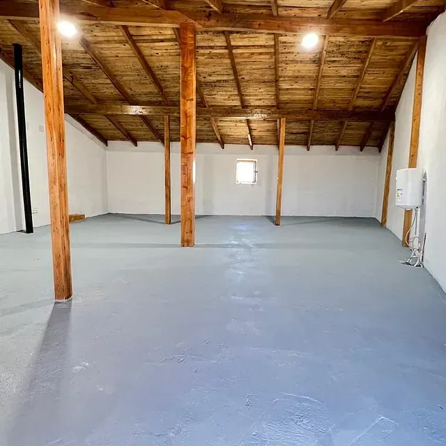 Una habitación vacía con un techo de madera y un suelo gris.