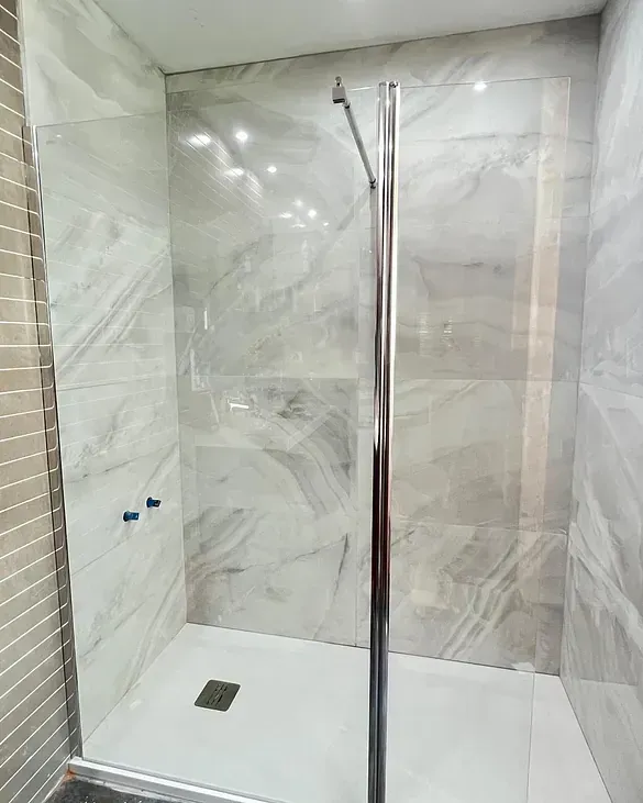 Un baño con ducha a ras de suelo y puerta de cristal.