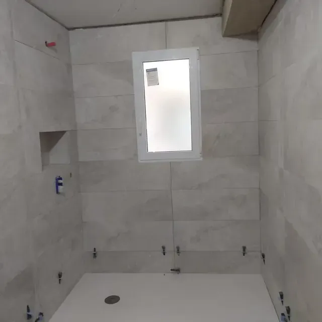 Un baño con paredes de azulejos y una ventana.