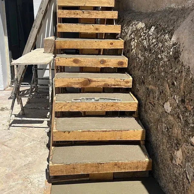 Se está construyendo una escalera de madera al lado de un muro de piedra.