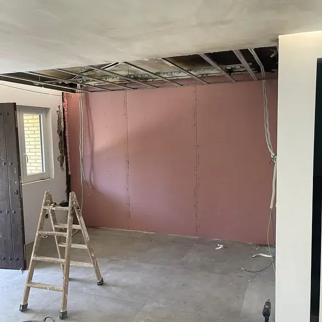 Una habitación con una pared rosa y una escalera de madera en ella.