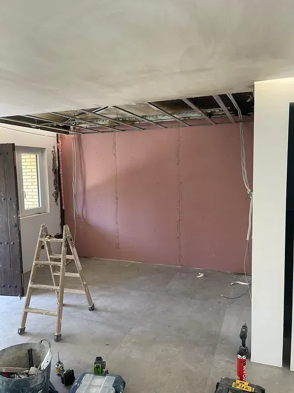 Una habitación con una pared rosa y una escalera de madera en ella.