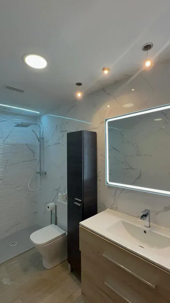 Un baño con inodoro, ducha y cabezal de ducha.