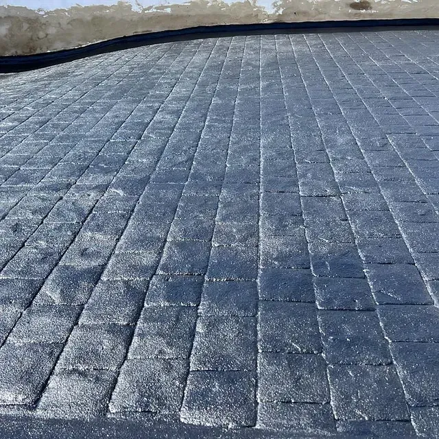 Un primer plano de un camino de entrada de ladrillo con un borde negro.