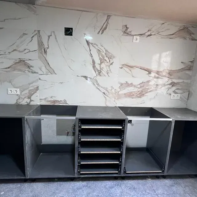 Una cocina con una pared de mármol y muchos gabinetes.
