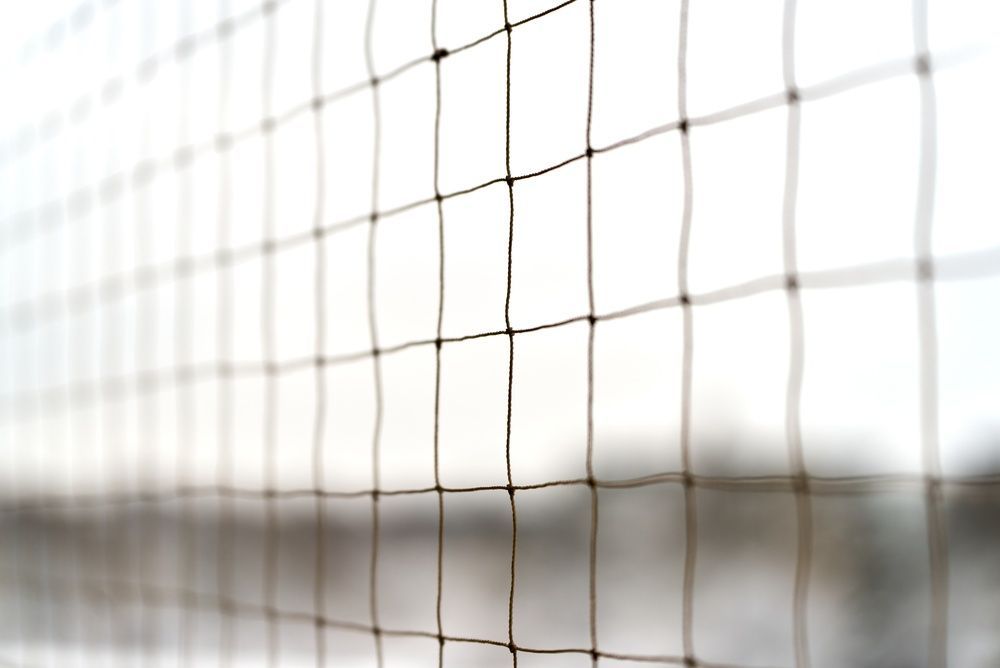 Primer plano de una red de voleibol sobre un fondo brillante y desenfocado.