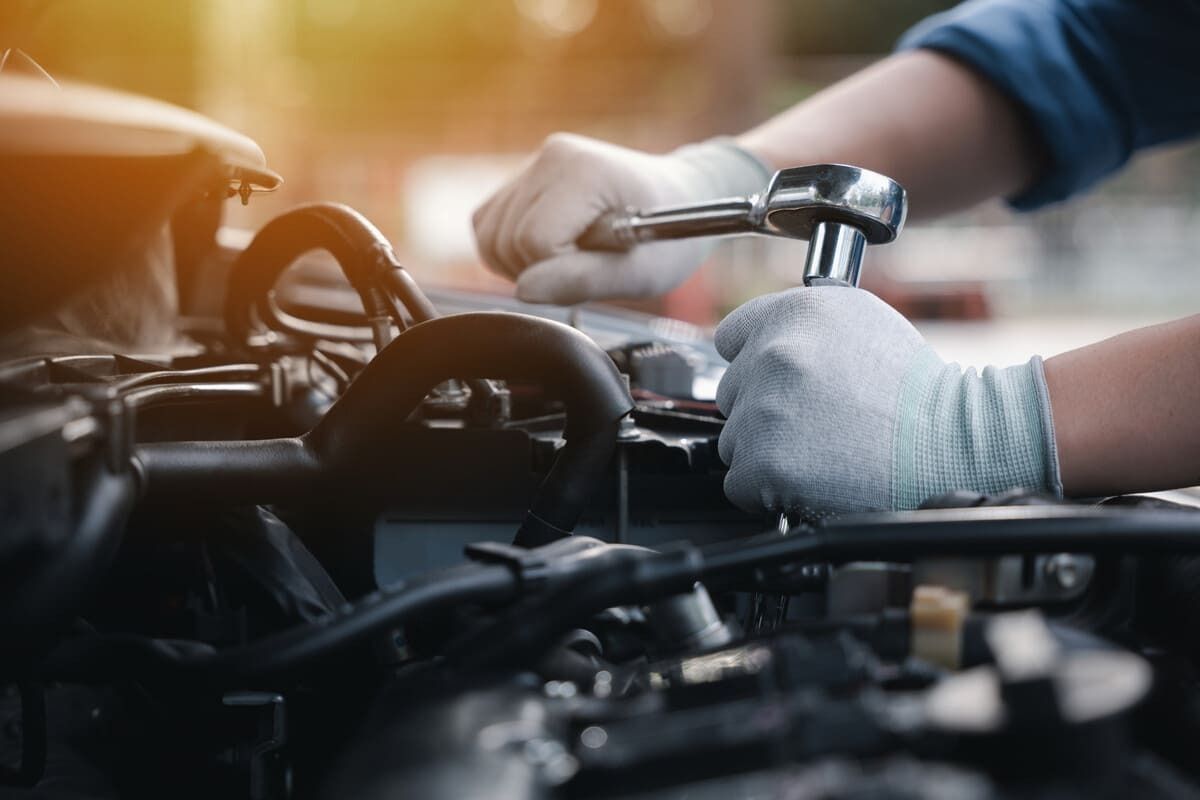 Un mecánico está trabajando en el motor de un automóvil con una llave inglesa.