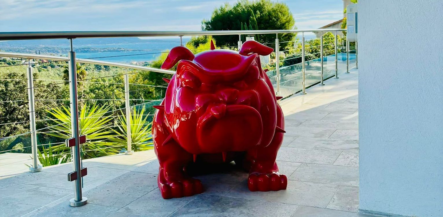 Objet décoratif d'art en forme de chien rouge sur un balcon.