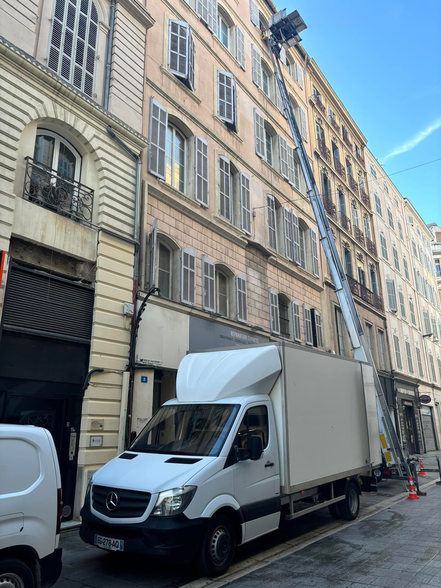 Camion de déménagement avec un morte-charge contre une façade.