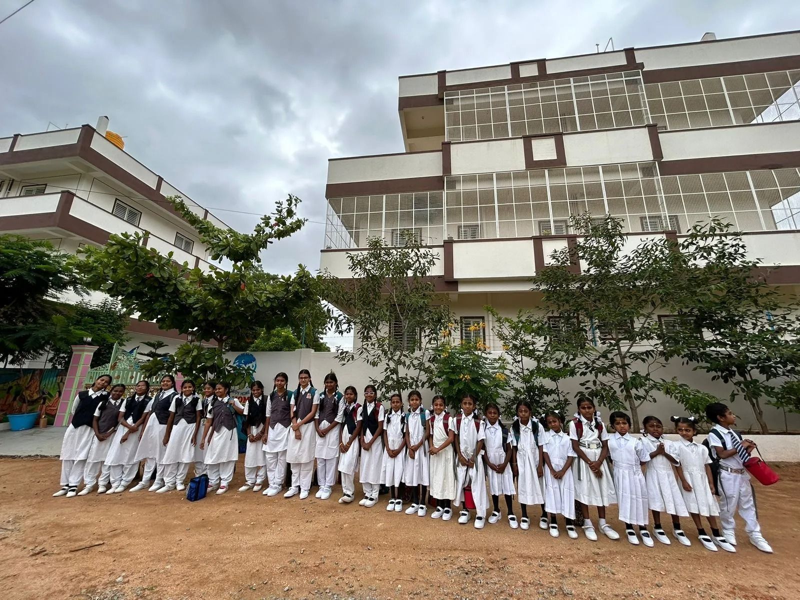 Scolari in uniforme che corrono sorridenti verso la telecamera. Sullo sfondo uno scuolabus giallo.