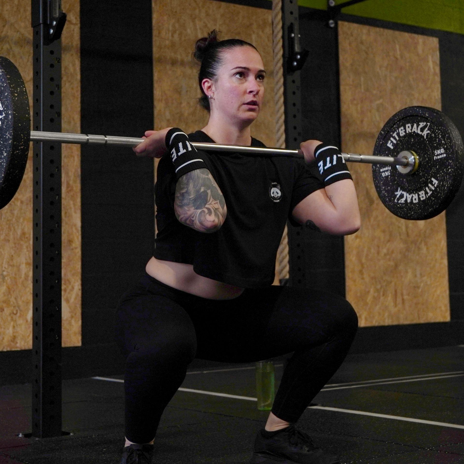 Une barre et une kettlebell sont posées sur le sol dans une salle de sport.
