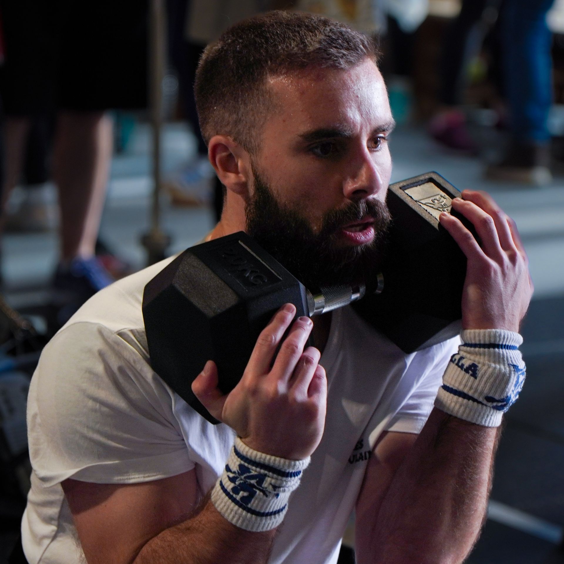 Un homme tient une kettlebell au-dessus de sa tête dans une salle de sport.