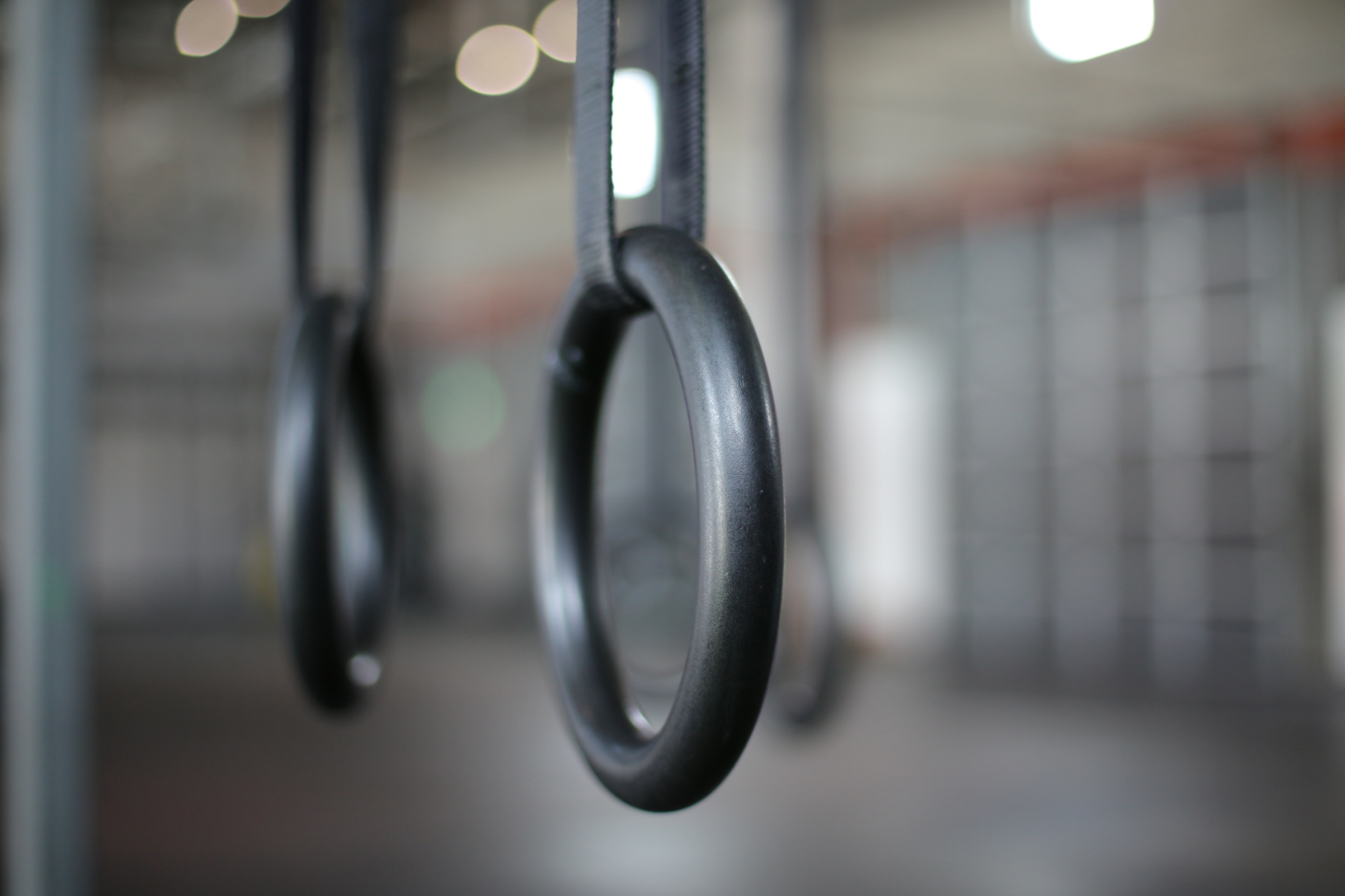 Un gros plan d'une paire d'anneaux de gymnastique suspendus à un poteau dans une salle de sport.