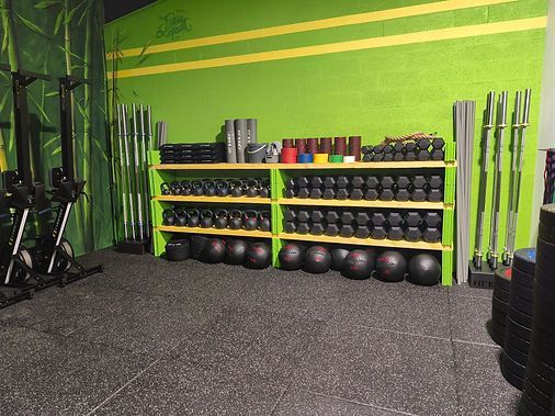 Une salle de sport avec beaucoup d'haltères sur des étagères et un mur végétal.