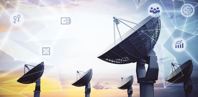 Satellite dishes with network icons against a sunset sky.