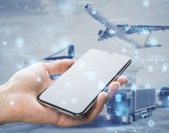 Hand holding smartphone with digital logistics overlay; airplane, truck, and port in background.
