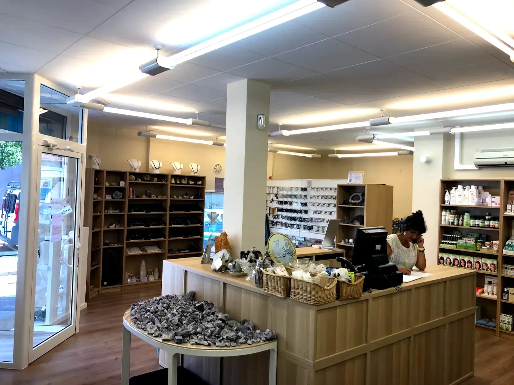 Interior de una tienda con mostrador de madera, estanterías y una persona detrás.