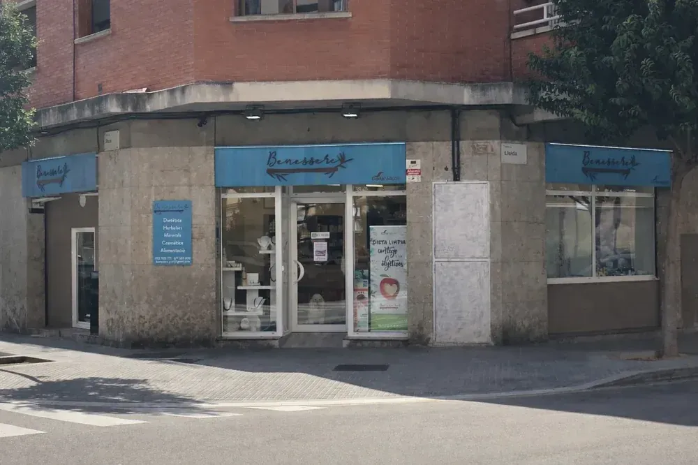 Tienda de esquina con cartel azul, escaparates y puerta de cristal.