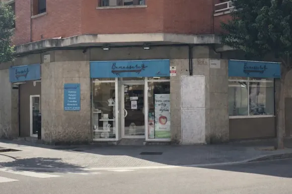 Tienda de esquina con cartel azul, escaparates y puerta de cristal.