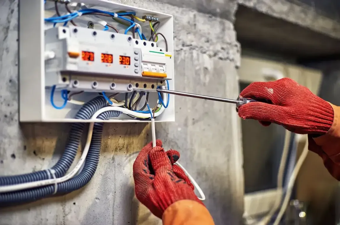 Una persona está trabajando en una caja eléctrica con un destornillador.