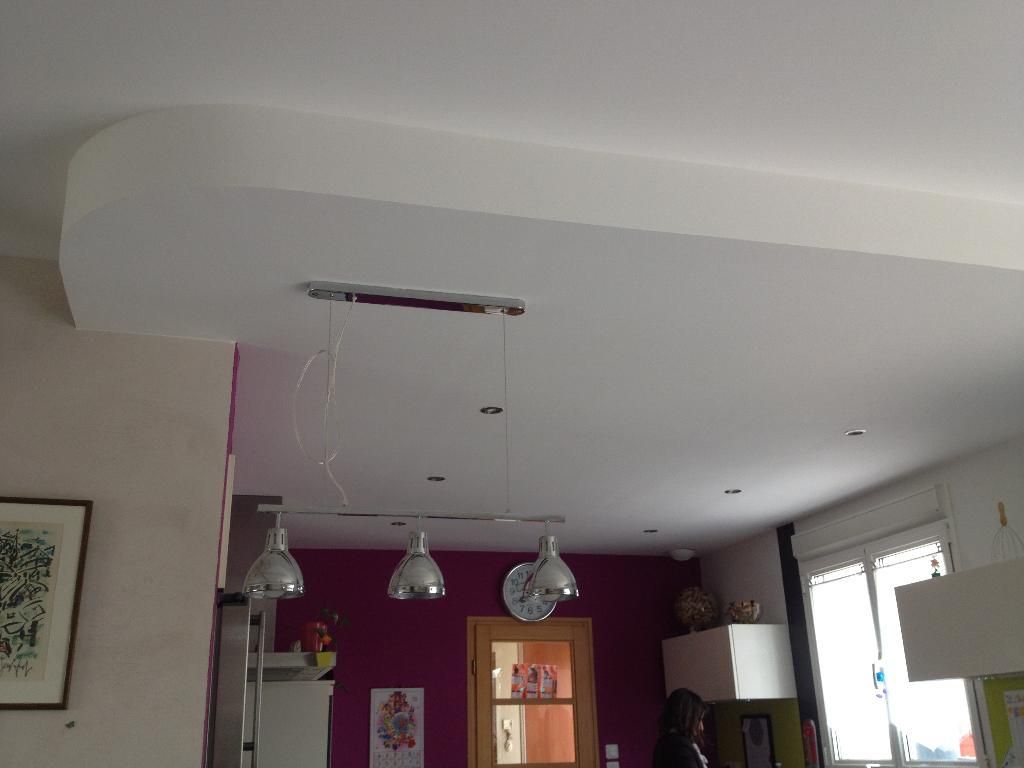 Plafond blanc avec une section incurvée, éclairage encastré et suspensions au-dessus de la cuisine.